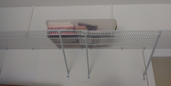 White metal wire shelves and plastic box on it.