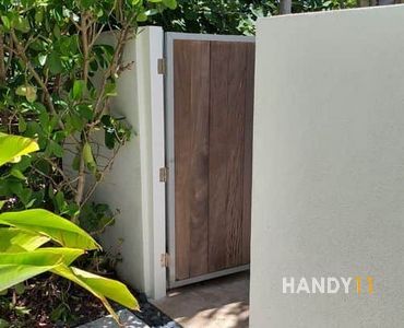 White concrete fence and brown ipe wood entrance door.