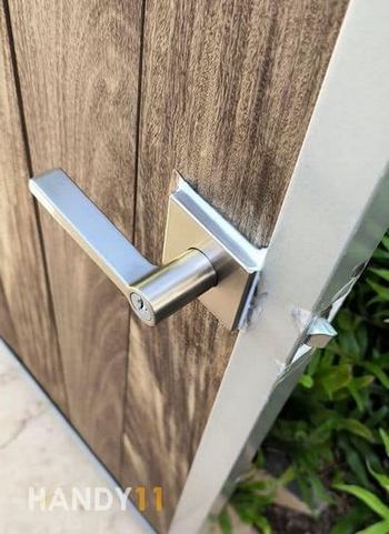 Grey metal lock installed to the brown door. Silicone around to protect from water.