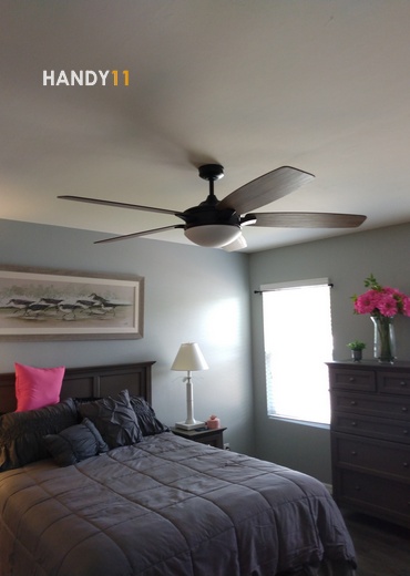 Ceiling fan, a bed and flowers in bedroom.
