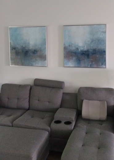 2 marine arts on wall and grey sofa in living room.