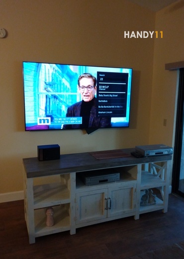 TV mounting whith in-wall wires and brown-white cabinet.