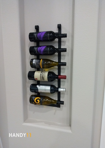 Wine holder with 6 botles of wine on the wall.