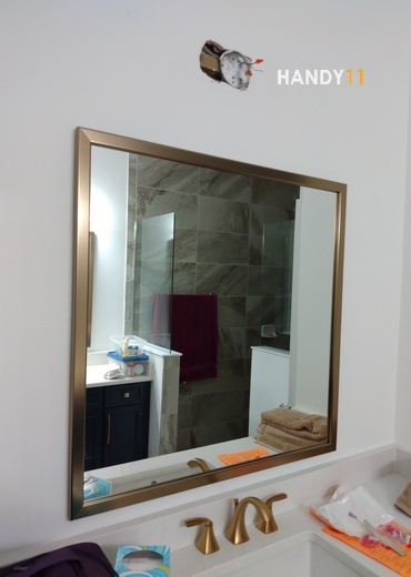 Big mirror hanged on the wall and golden focets in bathroom.