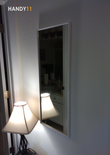 Square mirror hanged on the wall and table lamp lighting.
