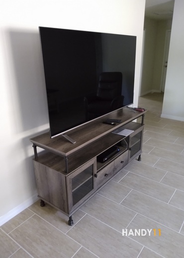 Brown-grey TV stand with a big TV on it.