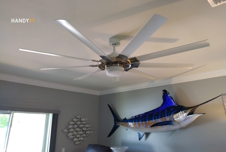 Ceiling fan with remote and big blue fish on the wall.